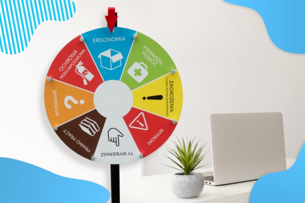 Koło fortuny o tematyce bhp i zdrowie stoi w biurze, obok laptop i kwiatek doniczkowy - gadżety bhp Proresult