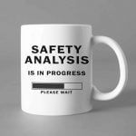 Na obrazku przedstawiony jest biały ceramiczny kubek z czarnym nadrukiem " Safety analysis" - Kubki BHP Proresult