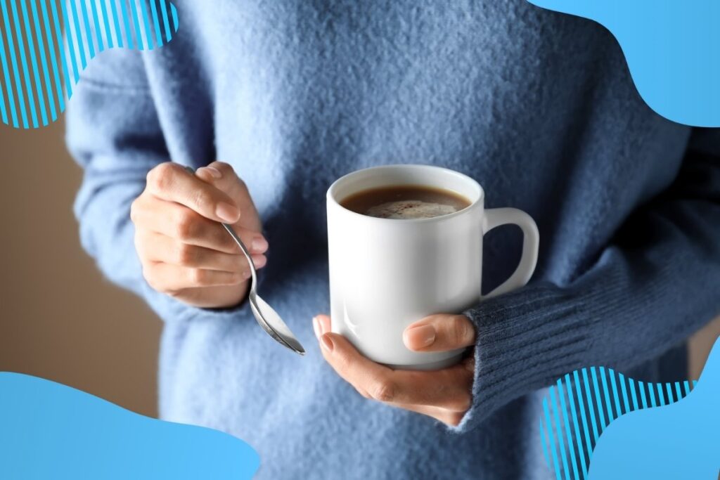 Na obrazku przedstawiona jest osoba w niebieskim sweterku trzymająca w dłoniach kubek z ciepłym napojem - NAJLEPSZE GADŻETY BHP W 2023 ROKU Proresult