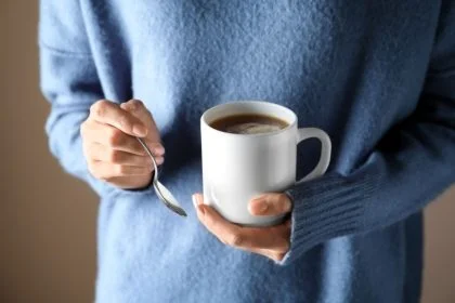 Na obrazku przedstawiona jest osoba w niebieskim sweterku trzymająca w dłoniach kubek z ciepłym napojem - NAJLEPSZE GADŻETY BHP W 2023 ROKU Proresult