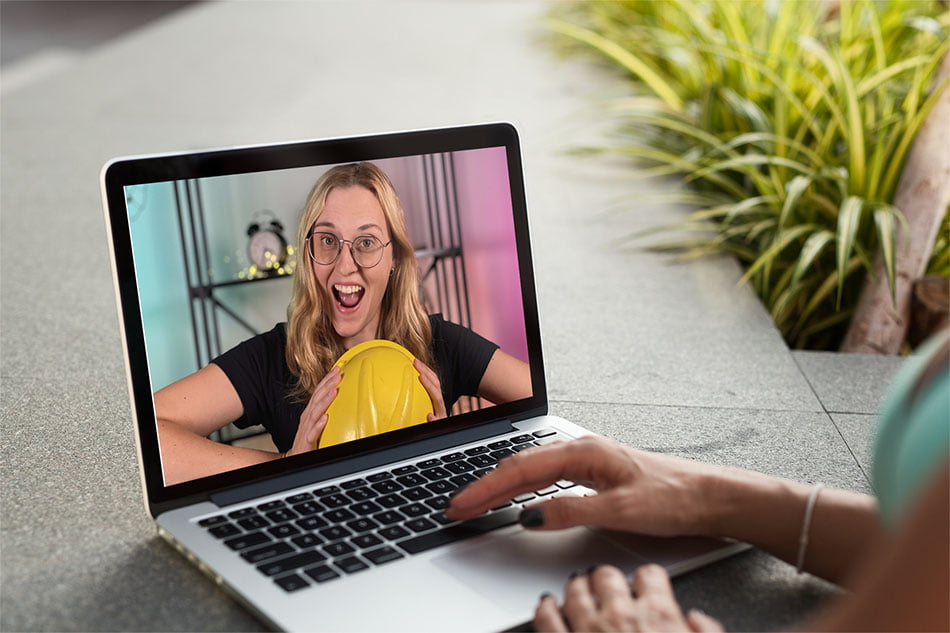 Dziewczyna pracuje przy laptopie, na monitorze widoczna szalona blondynka w czarnej koszulce, trzymająca hełm ochronny - e-learning bhp Proresult