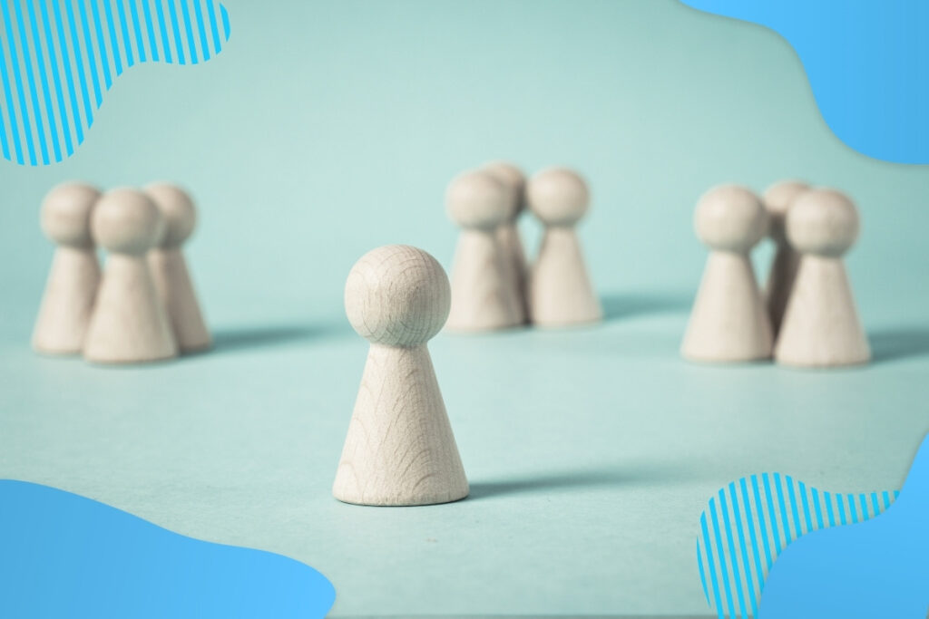Na niebieskim tle stoją drewniane pionki, jednak jeden pionek stoi sam - Proresult safety leadership, mobbing w miejscu pracy