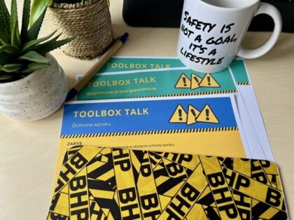 Na stole leżą kolorowe kartki Toolbox talk, kubek bhp oraz podkładka bhp pod myszkę - Toolbox talk, kwadranse dla bezpieczeństwa Proresult